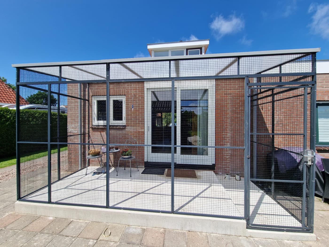 Antraciet kattenren over een terras, met gaasdak en loopdeur